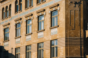 Windows on the beige facade of the house. Beautiful decorative architecture with with mosaics in the form of floral ornaments in Lviv, Ukraine.