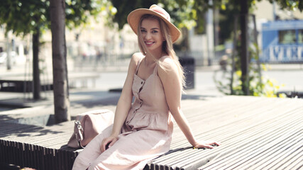 Portrait of beautiful blonde woman wearing hat spending time in a city.