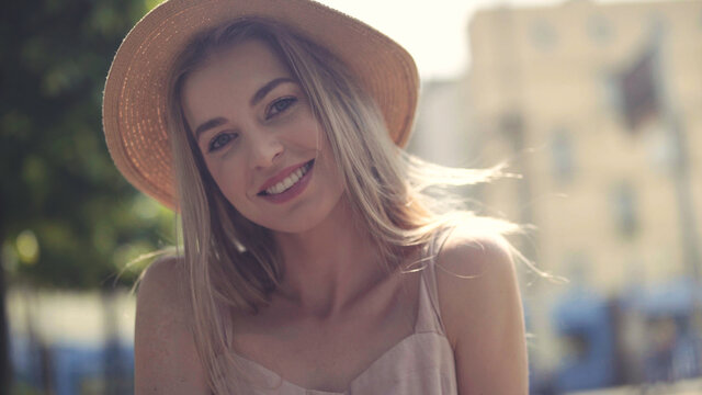 Portrait of beautiful blonde woman wearing hat spending time in a city.