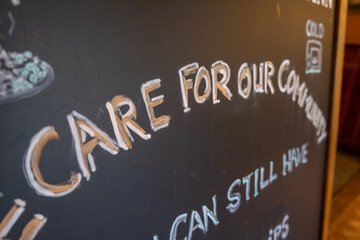 A handwritten sign at a pub saying care for our community as pubs and restaurants begin to open again as the covid lockdown eases in the UK
