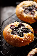 Blueberry sweet bun with butter crumble on a black background close up view