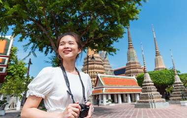 Woman traveler wall enjoying travel in an important Thai temple in Bangkok in her summer vacation.