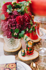 Festive table setting in red, using the national Russian toy - matryoshka. Nesting dolls.