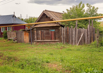 Old abandoned wooden house in the village. The windows are covered with boards. Dacha. Landscape.