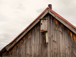 Wooden birdhouse under the roof of the house. Old house. House for birds. Rustic concept.