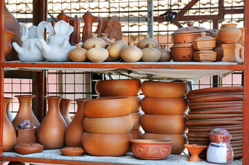Fototapeta na wymiar Ceramic clay terracotta jug, pot, vase, kitchen souvenirs on shelf at street handicraft pottery shop.