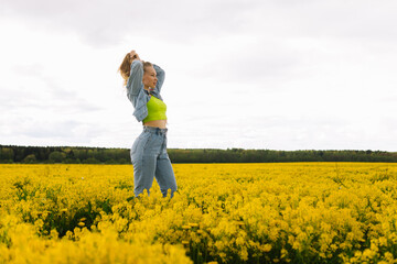 Fototapeta premium a blonde girl walks in a rapeseed field in the summer
