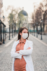 a brunette woman in orange clothes wearing white medical coat and a protective mask on her face