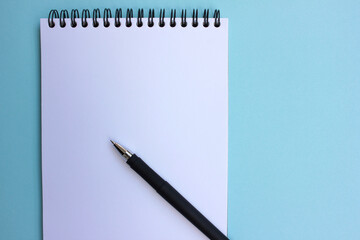 Open paper notebook with a black pen. on blue background. Back to school concept. Flat lay, copy space