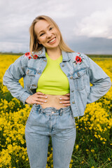 a blonde girl walks in a rapeseed field in the summer