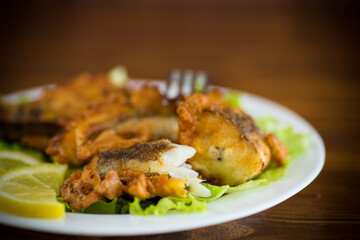 fried hake fish in batter with lettuce and lemon in a plate