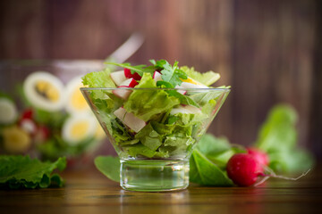 spring salad with arugula, boiled eggs, fresh radish, salad leaves in a glass bowl