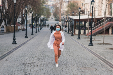 a brunette woman in orange clothes wearing white medical coat and a protective mask on her face