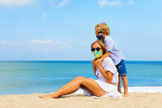 Mother, Child In Stylish Masks Have Fun On Sea Sand Beach. New Rules To Wear Face Covering At Public Places. Cancelled Cruise, Tour Due Coronavirus COVID 19. Family Summer Vacation, Travel Lifestyle.