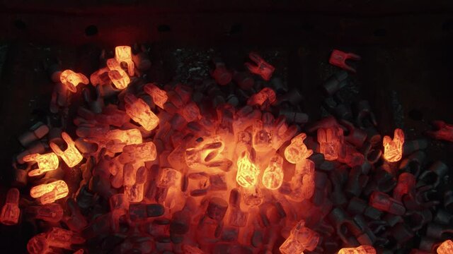 Red hot steel parts fall in collection bin to cool, forging manufacturing plant