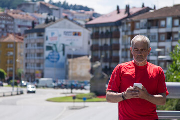 mature man doing sports and using mobile phone in the city
