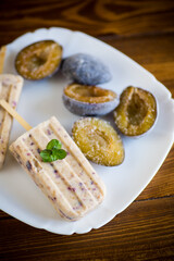 plum sweet homemade ice cream on a stick with slices of plum inside, in a plate