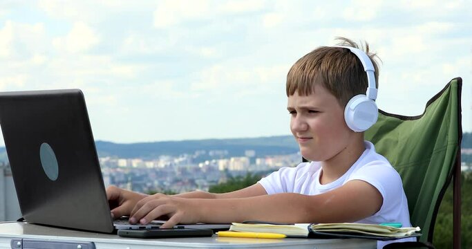 the boy in headphones studies at the computer, makes notes in the notebook and looks at monocular telescope