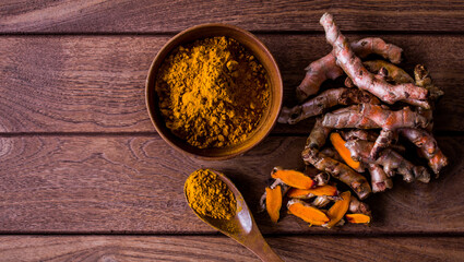 Fresh turmeric root and turmeric powder in plate wood. This is a very useful herbal medicine or herbs for health. Presents in a natural background.