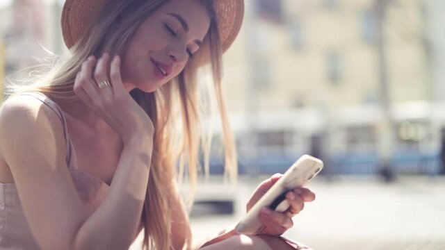 Young blonde woman using phone in a city.