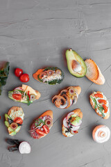 various beautiful bruschettas with vegetables, avocado, salami, cheese, tomatoes, guacamole, olives and radishes 