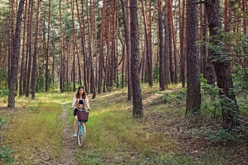Obraz premium Young woman riding a bike in pine forest