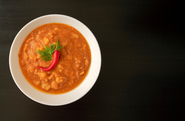 Famous traditional Arabic cuisine - peeled fava beans with chili in white bowl on dark wooden background with copy space. Top view. Foul Mudammas, egyptian beans.