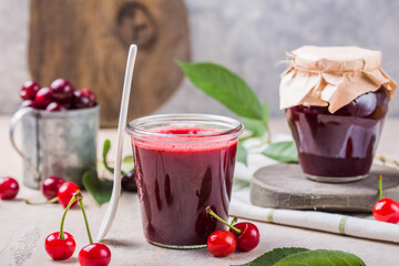 Homemade sweet and sour cherry jam with fresh cherries on light table, copy space