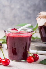 Homemade sweet and sour cherry jam with fresh cherries on light table, copy space