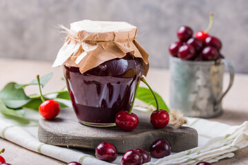 Homemade sweet and sour cherry jam with fresh cherries on light table, copy space