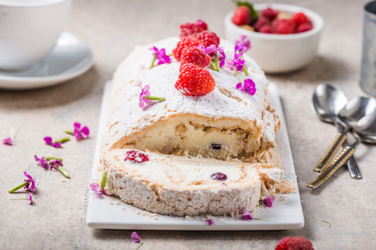 Meringue roll cake with cream and raspberries. Roulade, summer dessert, closeup.