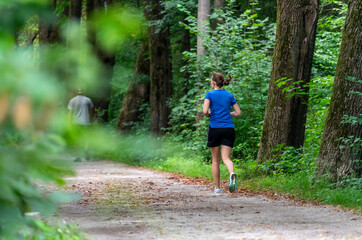 Joggen / Laufen in den Isar-Auen am Flaucher in München: aktive junge Frau beim Running