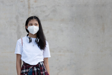 Asian young woman standing on public place while wearing face mask as protection against infectious diseases outdoors during coronavirus pandemic. Basic equipment to help keep us safe new life.