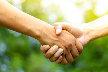 A male close up holding a hand between two colleagues who have a good relationship concept in a...