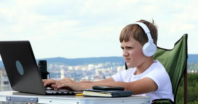 the boy is studying at the computer, something is wrong fail with him and he is looking through a monocular telescope