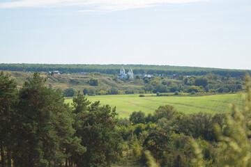 Obraz premium Rural landscape, lots of green grass and trees from which the Orthodox church looks out.