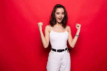 Portrait of a satisfied casual girl celebrating success isolated over red background