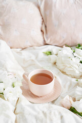 Breakfast in bed in hotel room. Accommodation. Breakfast in bed with tea cup and flowers on bed background top view. Copy Space. Romantic valentine's day breakfast. Cozy morning. Happy Mother's Day