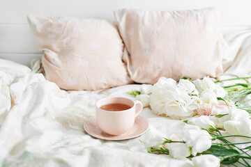 Breakfast in bed in hotel room. Accommodation. Breakfast in bed with tea cup and flowers on bed...