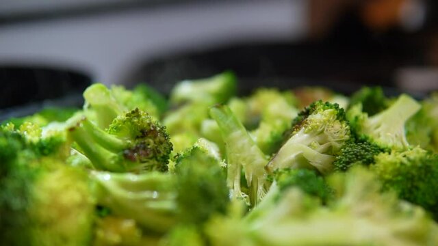 Fresh steamed broccoli smoking in the skillet or wok - slow pull back close up