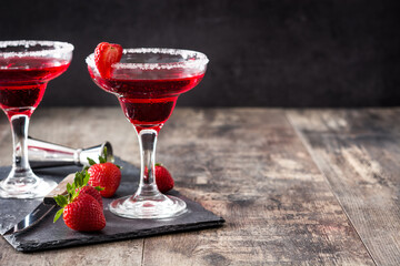 Strawberry red cocktail in glass on wooden table. Copy space