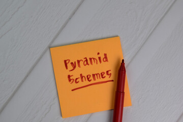 Pyramid Schemes write on sticky notes isolated on office desk.