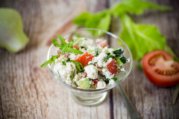 fresh cottage cheese salad with cucumbers and tomatoes with herbs in a bowl