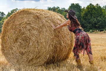 Naklejka na ściany i meble Beautiful cowboy woman Posing near at the haystacks, Fashion concept.