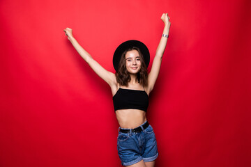 Naklejka premium Young woman with hands up win gesture isolated over red background