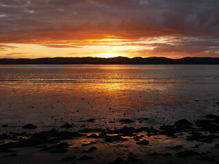Obraz premium sunset over the hills and water, dramatic grey clouds