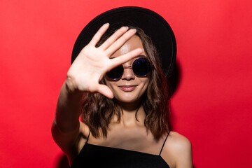 Young beautiful woman doing stop sing with palm of the hand over red background. Warning expression with negative and serious gesture on the face.