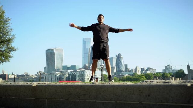 Slow motion shot of man doing jumping jack in city