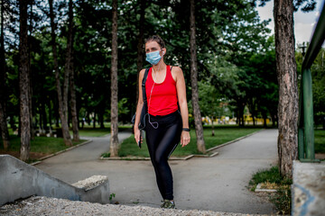Young  Caucasian woman with protective face mask on her way to training in a public park.
