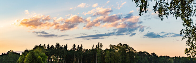 Panorama, sunset over fields and Austrian village with dramatic sky and colorful clouds